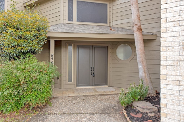 doorway to property featuring a shingled roof