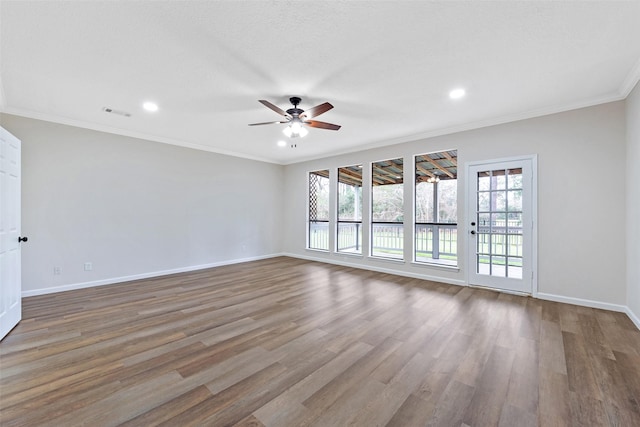 spare room featuring a ceiling fan, wood finished floors, recessed lighting, crown molding, and baseboards