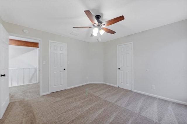 carpeted empty room featuring visible vents, a ceiling fan, and baseboards