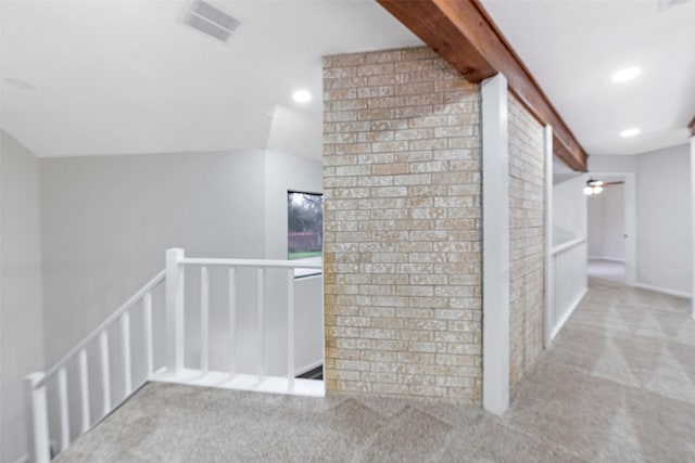 hall with visible vents, an upstairs landing, beam ceiling, and brick wall