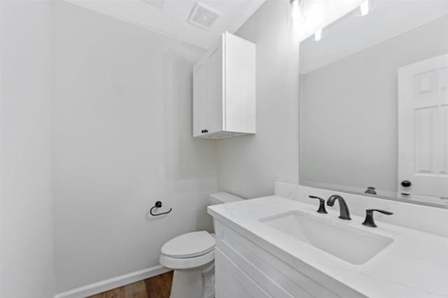 bathroom featuring visible vents, baseboards, toilet, wood finished floors, and vanity