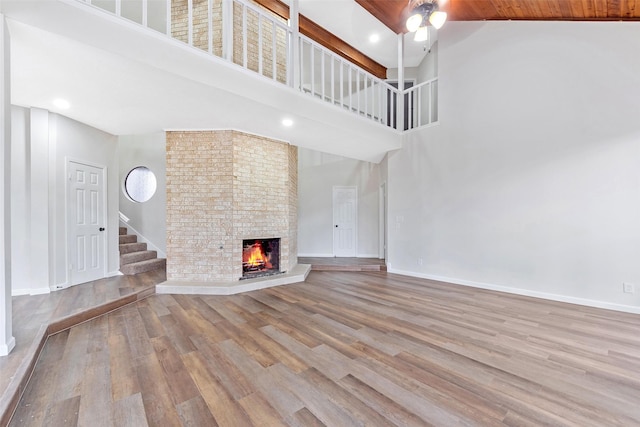 unfurnished living room featuring a fireplace, stairway, wood finished floors, and baseboards