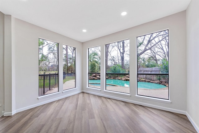 spare room featuring recessed lighting, wood finished floors, and baseboards