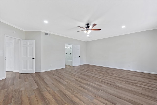 empty room with visible vents, baseboards, wood finished floors, and ornamental molding