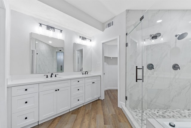 bathroom with wood finished floors, visible vents, a marble finish shower, and a sink