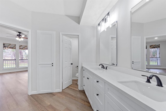 full bath featuring double vanity, toilet, wood finished floors, and a sink