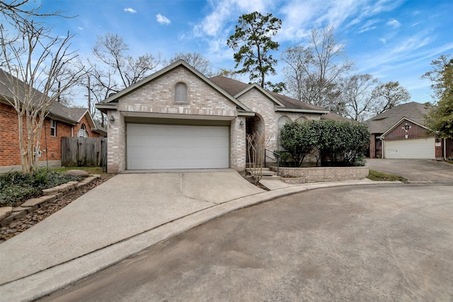 single story home with a garage, brick siding, driveway, and fence