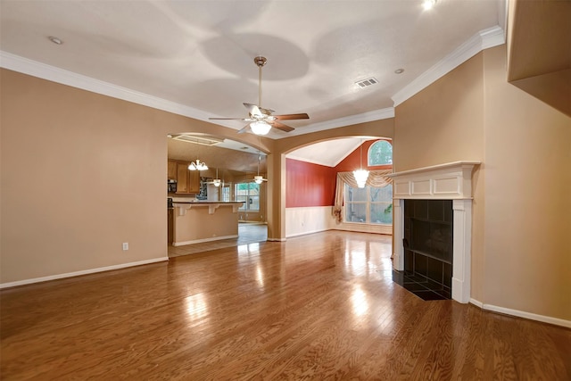 unfurnished living room featuring wood finished floors, a ceiling fan, visible vents, ornamental molding, and a tiled fireplace