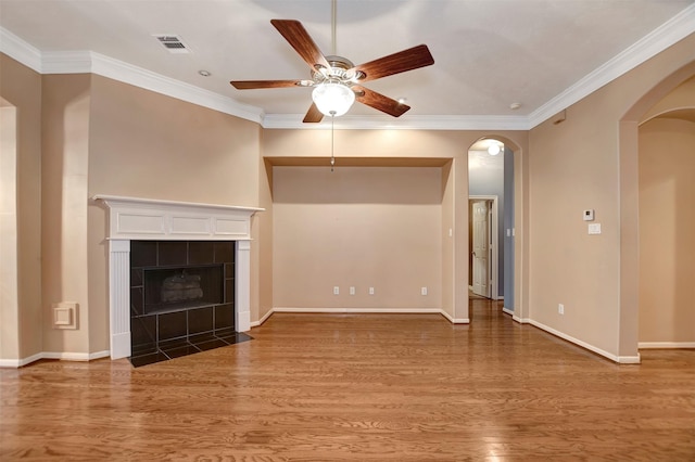 unfurnished living room featuring wood finished floors, arched walkways, visible vents, and ceiling fan