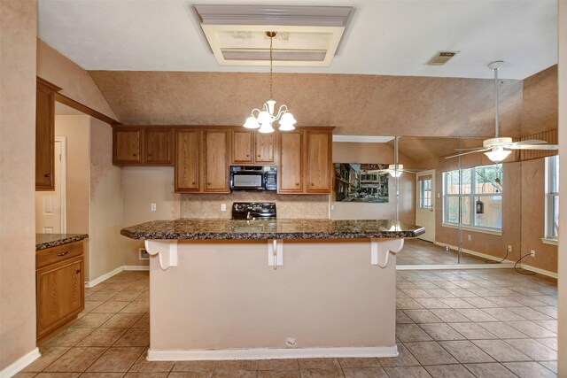 kitchen with visible vents, a breakfast bar area, decorative backsplash, brown cabinets, and black appliances