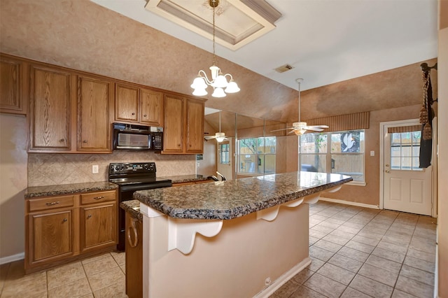 kitchen with dark countertops, brown cabinets, black appliances, and lofted ceiling