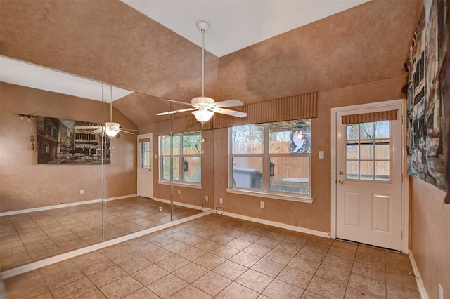 tiled entryway featuring baseboards, ceiling fan, and vaulted ceiling