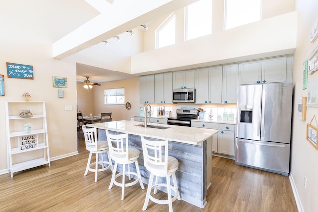 kitchen featuring a sink, stainless steel appliances, a kitchen bar, and light wood-style floors