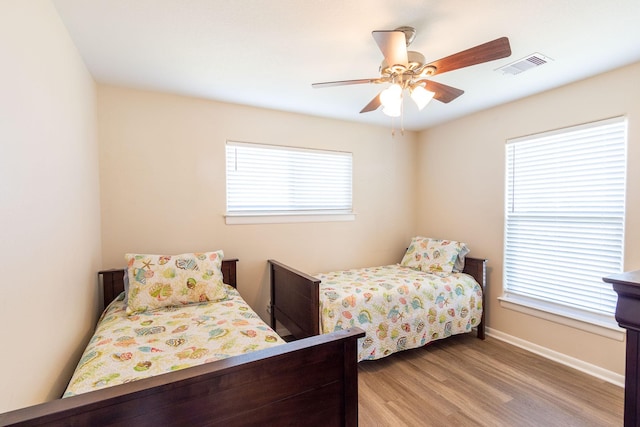 bedroom with a ceiling fan, baseboards, visible vents, and light wood finished floors