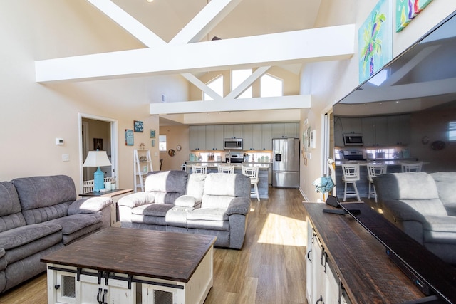 living area with light wood-style flooring and high vaulted ceiling