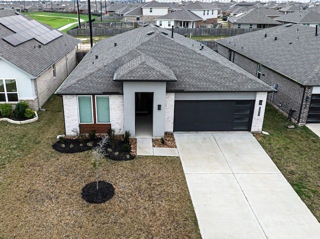 view of front facade featuring a residential view, brick siding, an attached garage, and a shingled roof