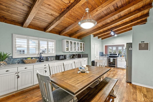 dining space with baseboards, wood ceiling, vaulted ceiling with beams, and light wood finished floors