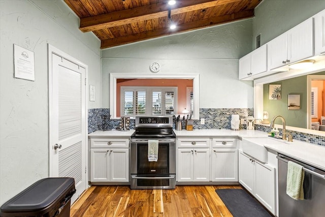 kitchen with vaulted ceiling with beams, light countertops, wooden ceiling, stainless steel appliances, and a sink