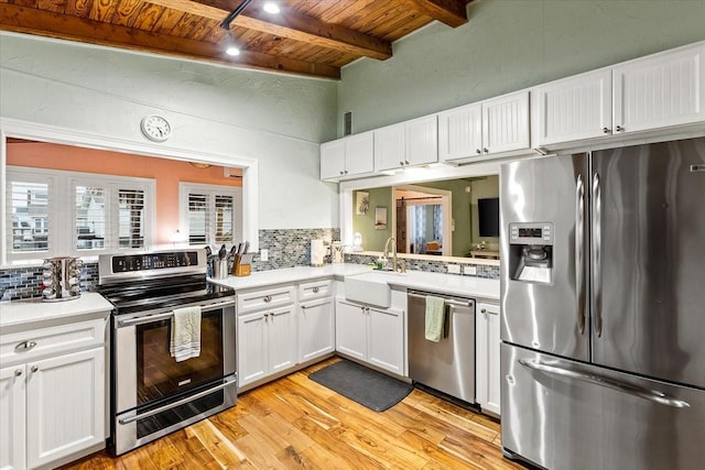 kitchen featuring a sink, backsplash, stainless steel appliances, light countertops, and wood ceiling