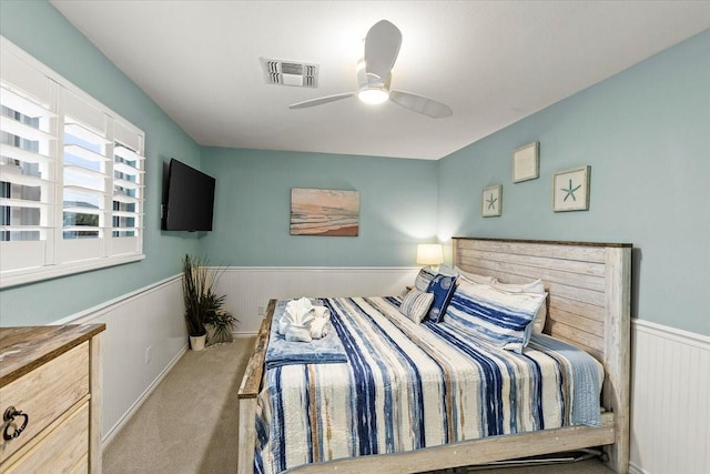 bedroom featuring a wainscoted wall, carpet flooring, a ceiling fan, and visible vents