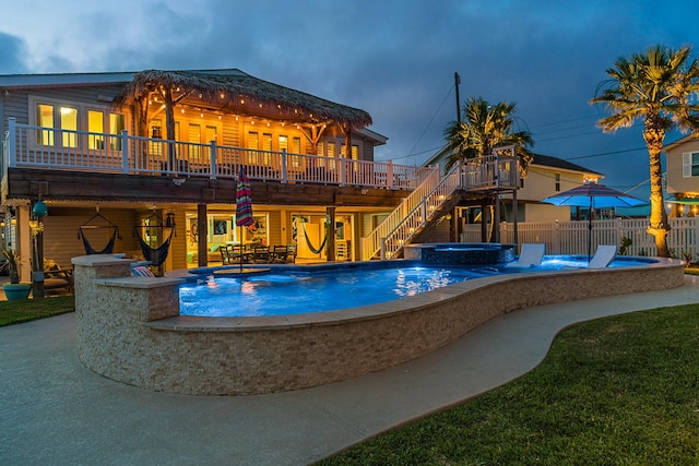 view of pool featuring a patio, fence, a wooden deck, a pool with connected hot tub, and stairs