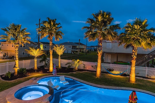 view of pool featuring an in ground hot tub, fence private yard, a residential view, and a lawn