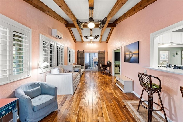 living room with beam ceiling, ceiling fan, an AC wall unit, and a barn door