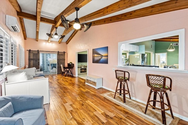 living room with a ceiling fan, a wall mounted AC, lofted ceiling with beams, wood finished floors, and a barn door