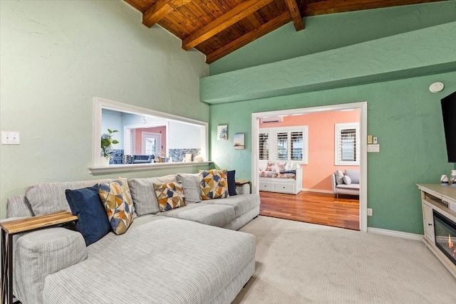 carpeted living area with beamed ceiling, wood ceiling, baseboards, and a glass covered fireplace