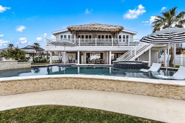 rear view of house featuring stairway, a balcony, an in ground hot tub, an outdoor pool, and a patio area