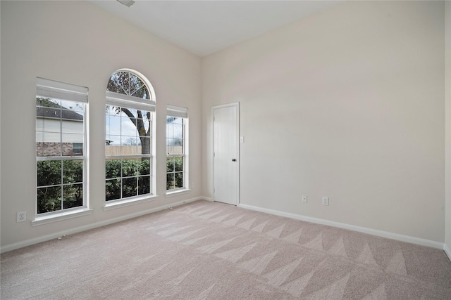 unfurnished room featuring baseboards, light carpet, and a towering ceiling