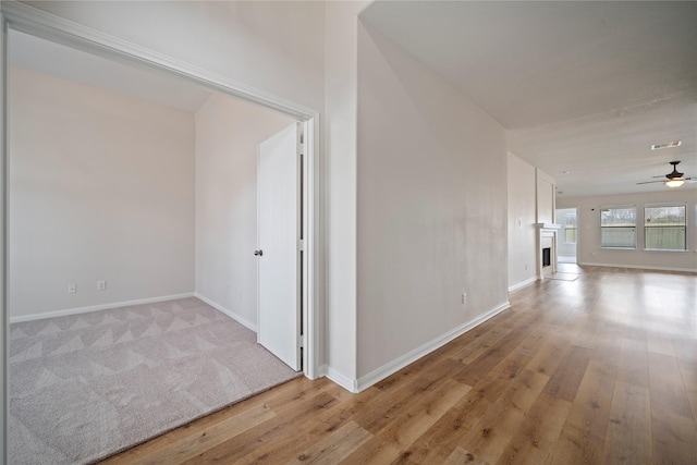 hall featuring visible vents, baseboards, and light wood-style floors