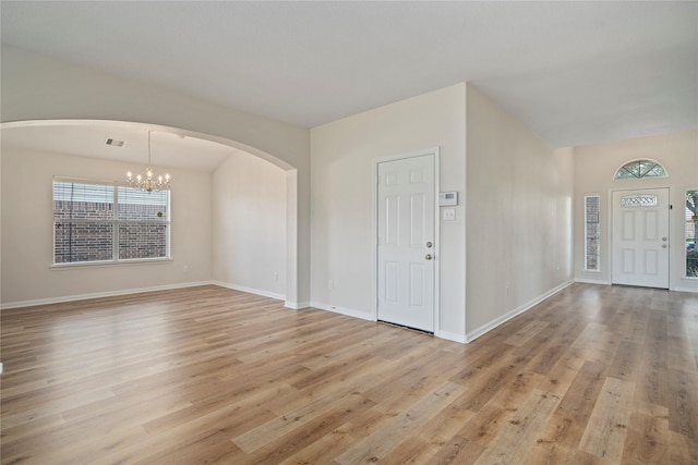 entrance foyer with visible vents, baseboards, a chandelier, light wood-type flooring, and arched walkways