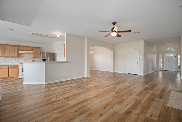 unfurnished living room with arched walkways, visible vents, light wood-type flooring, and ceiling fan