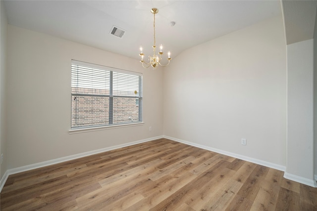 empty room with wood finished floors, visible vents, baseboards, an inviting chandelier, and lofted ceiling