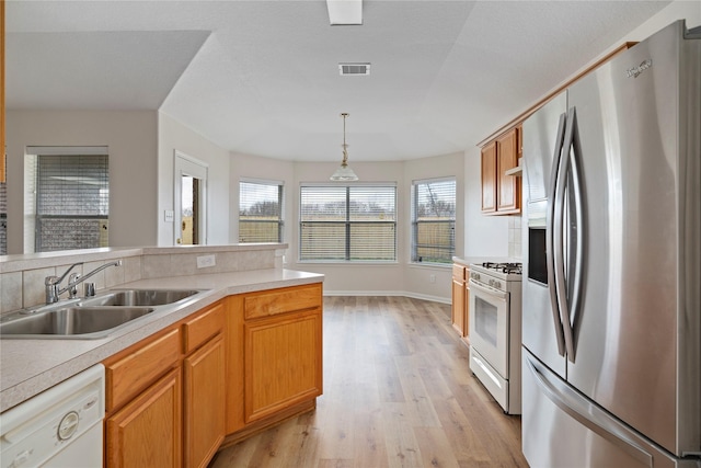 kitchen with white appliances, visible vents, a sink, light countertops, and light wood-type flooring