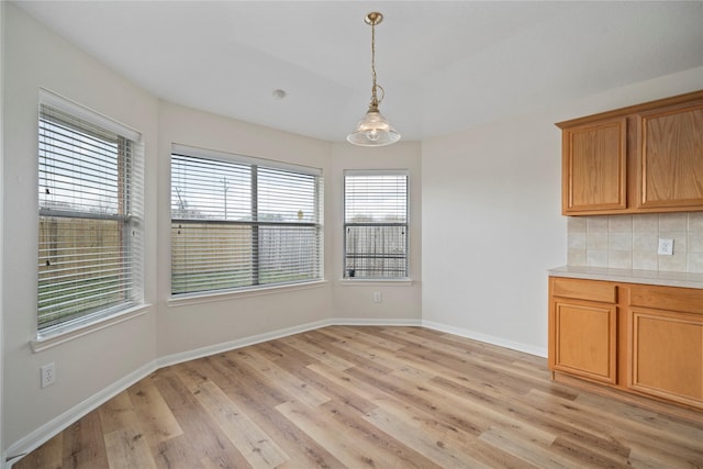 unfurnished dining area with baseboards and light wood finished floors