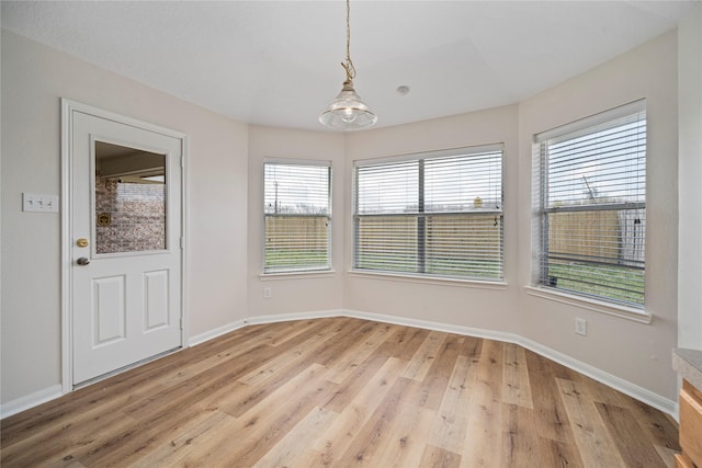 unfurnished dining area featuring baseboards and light wood-style floors