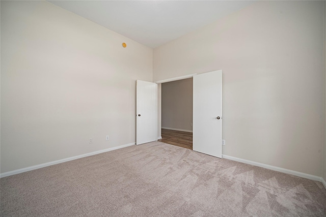 unfurnished room featuring a towering ceiling, baseboards, and carpet floors