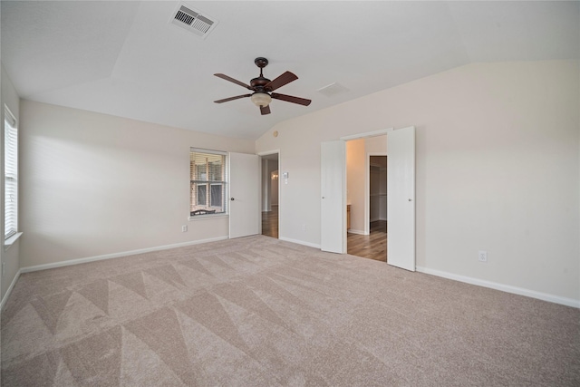 carpeted spare room featuring vaulted ceiling, baseboards, and visible vents