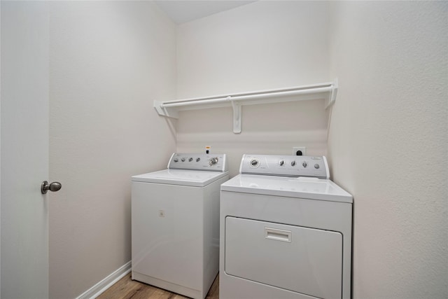 laundry room featuring washing machine and clothes dryer, laundry area, light wood-style flooring, and baseboards