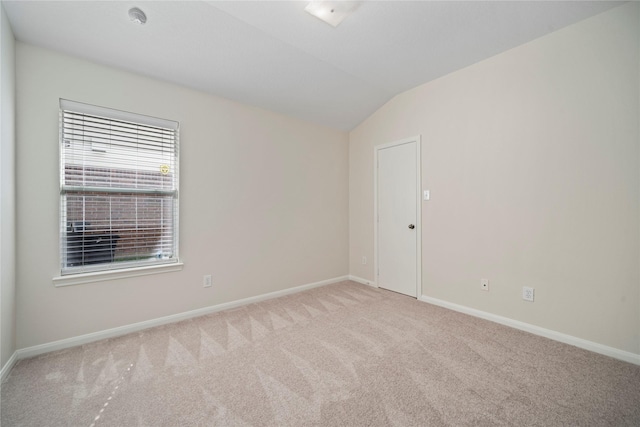 carpeted spare room with baseboards and vaulted ceiling