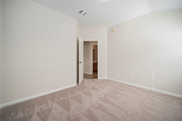 empty room featuring vaulted ceiling, baseboards, visible vents, and light carpet