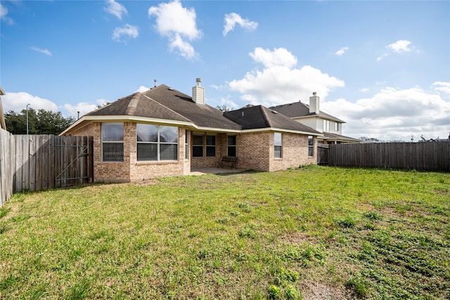 rear view of house with brick siding, a fenced backyard, a lawn, and a patio area