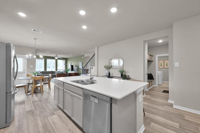 kitchen with a kitchen island with sink, appliances with stainless steel finishes, light wood-type flooring, and a sink