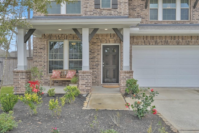 view of exterior entry featuring a garage, brick siding, and a porch