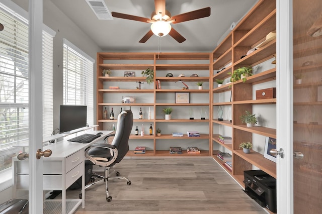 office with light wood finished floors, visible vents, and ceiling fan