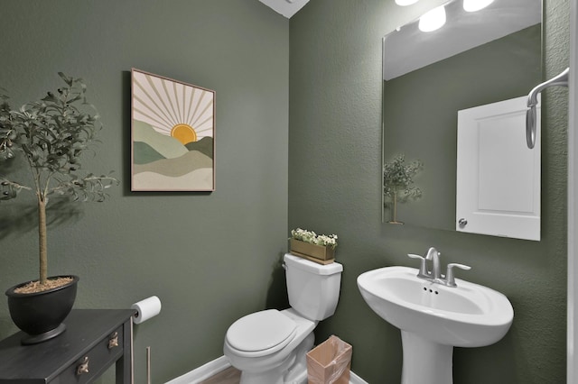 bathroom featuring toilet, baseboards, and a sink