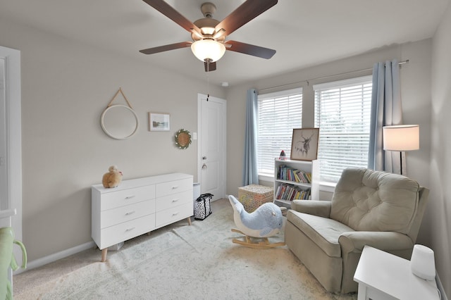 sitting room with baseboards, light colored carpet, and a ceiling fan