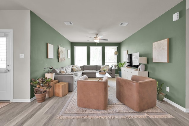 living area with baseboards, wood finished floors, visible vents, and ceiling fan